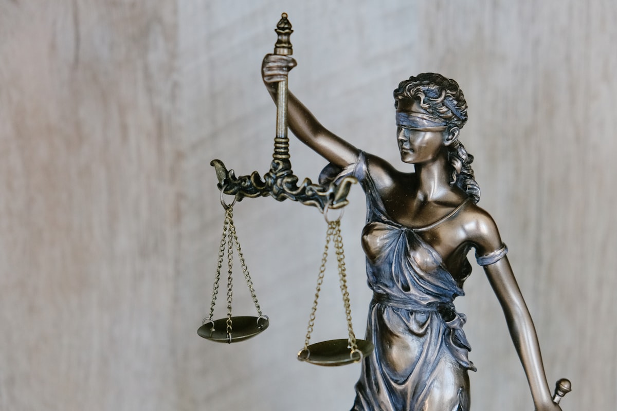 Estátua da justiça com balança sobre mesa de escritório de advocacia